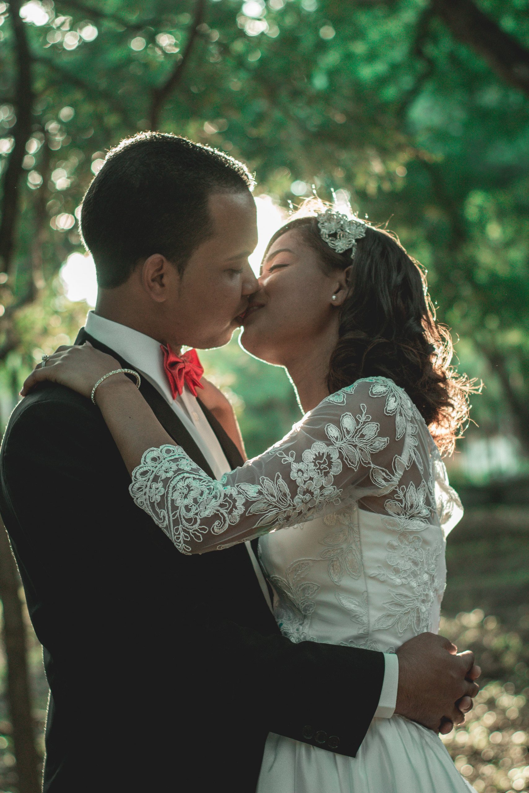 bride and groom kissing under a tree with greenery in the background